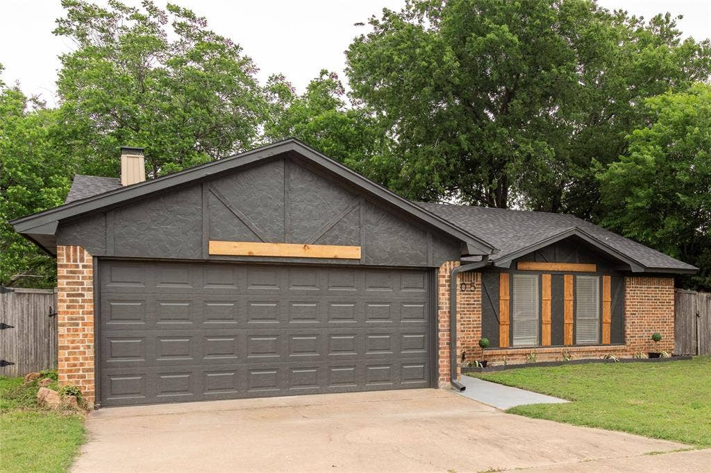 1205 Augusta Road, Benbrook, TX 76126 Exterior featuring a brick facade, a dark gray garage door, and a contrasting dark gray gable with wood accents