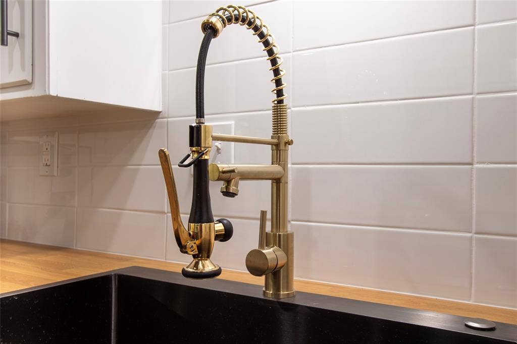 1205 Augusta Road, Benbrook, TX 76126 Gold-tone kitchen faucet with a pull-down sprayer, set against a white subway tile backsplash