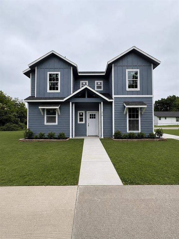 316 Henry Street, Waxahachie, TX 75165 Two-story residence featuring a blue board and batten facade with white trim, a covered entry porch, multiple window awnings, and a concrete pathway leading to the front door