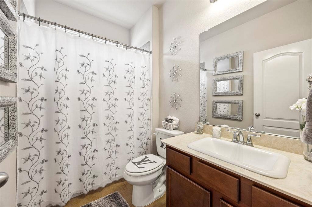 1437 Tanglewood Trail, Northlake, TX 76226 Bathroom featuring a single vanity with wood cabinetry, a light-toned countertop, and an integrated rectangular sink