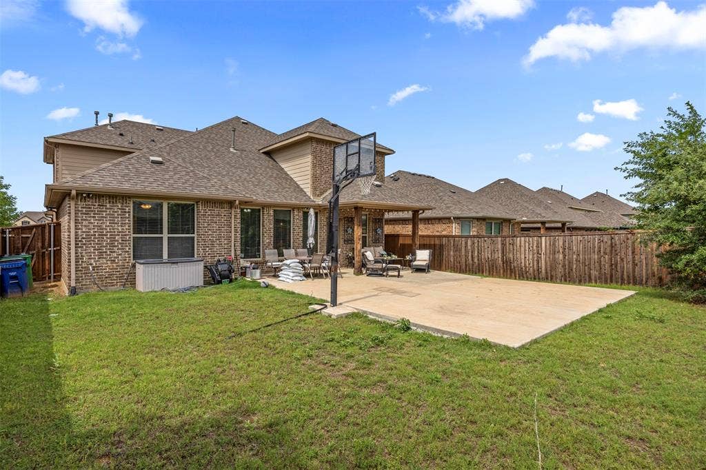 1437 Tanglewood Trail, Northlake, TX 76226 Expansive backyard featuring a large concrete patio, a wood privacy fence, and a two-story brick exterior with siding accents
