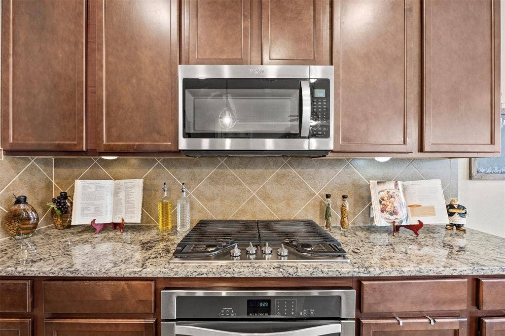 1437 Tanglewood Trail, Northlake, TX 76226 Kitchen featuring stone countertops, stainless steel appliances, wood cabinetry, built-in microwave, and tiled backsplash