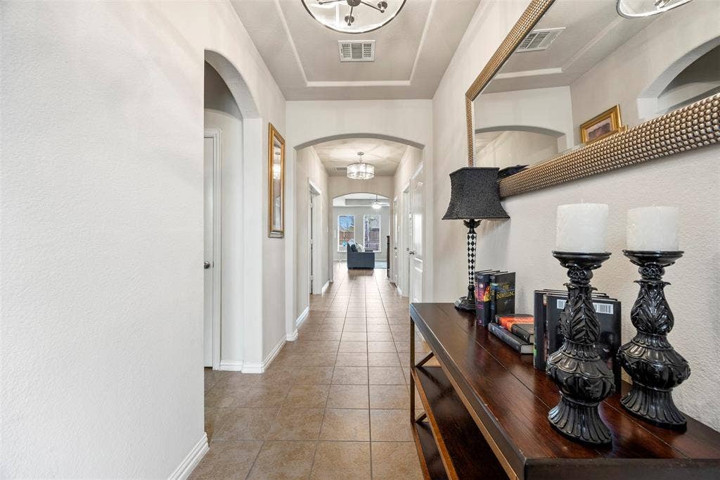 1437 Tanglewood Trail, Northlake, TX 76226 Long hallway featuring tile flooring, arched doorways, a coffered ceiling, and recessed lighting