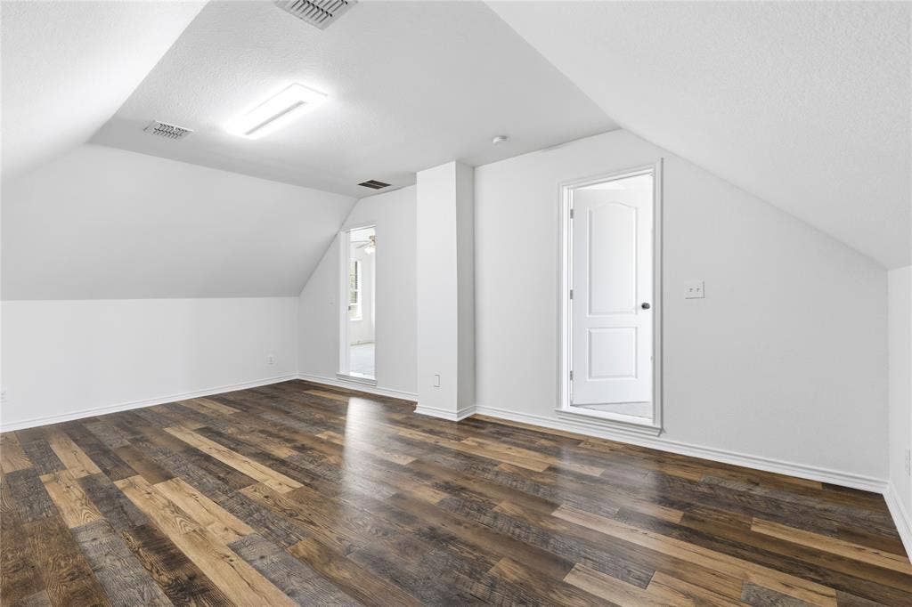 544 Hubbard Circle, Nevada, TX 75173 Spacious room featuring sloped ceilings, wood-finish flooring, recessed lighting, and a white paneled door