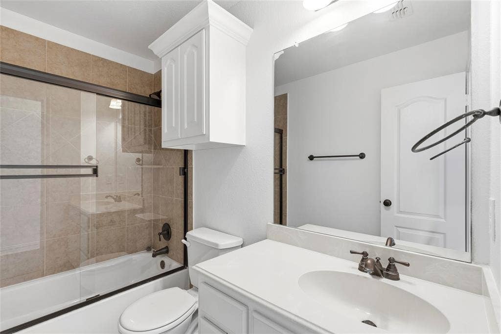 544 Hubbard Circle, Nevada, TX 75173 Full bathroom featuring a white vanity with an undermount sink and oil-rubbed bronze fixtures, a framed mirror, and a white toilet