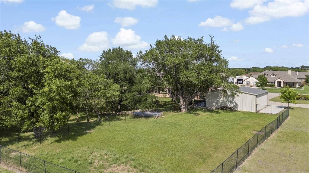 544 Hubbard Circle, Nevada, TX 75173 Expansive outdoor area featuring a metal utility shed, mature trees, and perimeter fencing