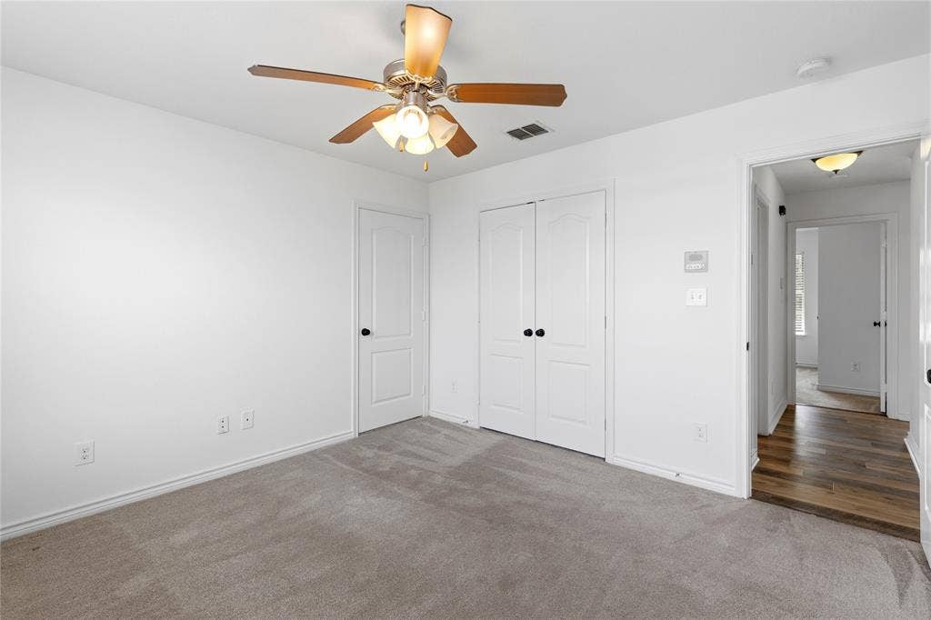 544 Hubbard Circle, Nevada, TX 75173 Neutral gray carpeted room featuring a ceiling fan with integrated lighting, a double-door closet, and a white paneled door