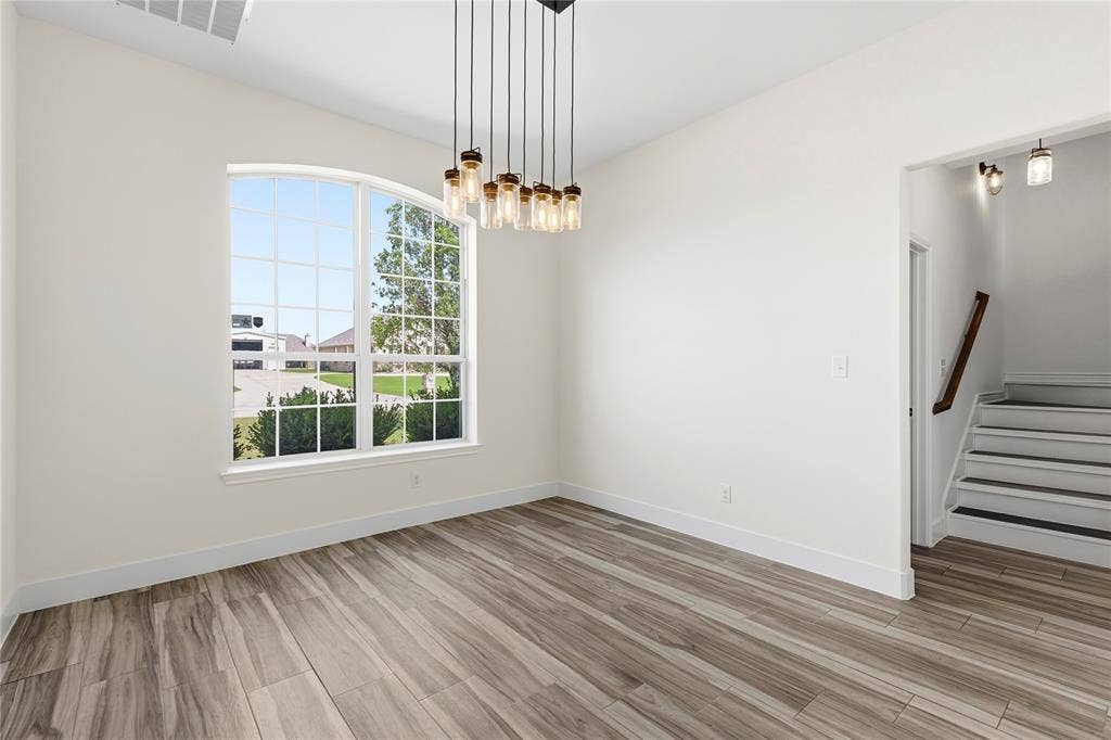 544 Hubbard Circle, Nevada, TX 75173 Room featuring an arched grid window, wood-finish flooring, and a contemporary multi-bulb chandelier