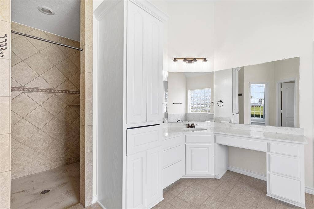 544 Hubbard Circle, Nevada, TX 75173 Spacious vanity area featuring white cabinetry with a built-in dressing table, expansive wall-mounted mirror, and a single basin with a contemporary faucet