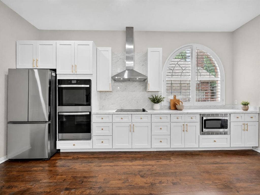 4437 Lone Tree Drive, Plano, TX 75093 Modern kitchen featuring white cabinetry, stainless steel appliances, marble-look backsplash, and wood-finish flooring
