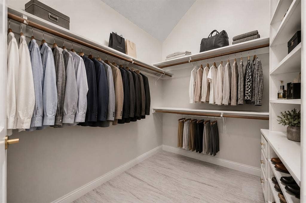 4437 Lone Tree Drive, Plano, TX 75093 Spacious walk-in closet featuring light wood-finish flooring, ample hanging rods, built-in shelving, and integrated drawers with gold-tone hardware