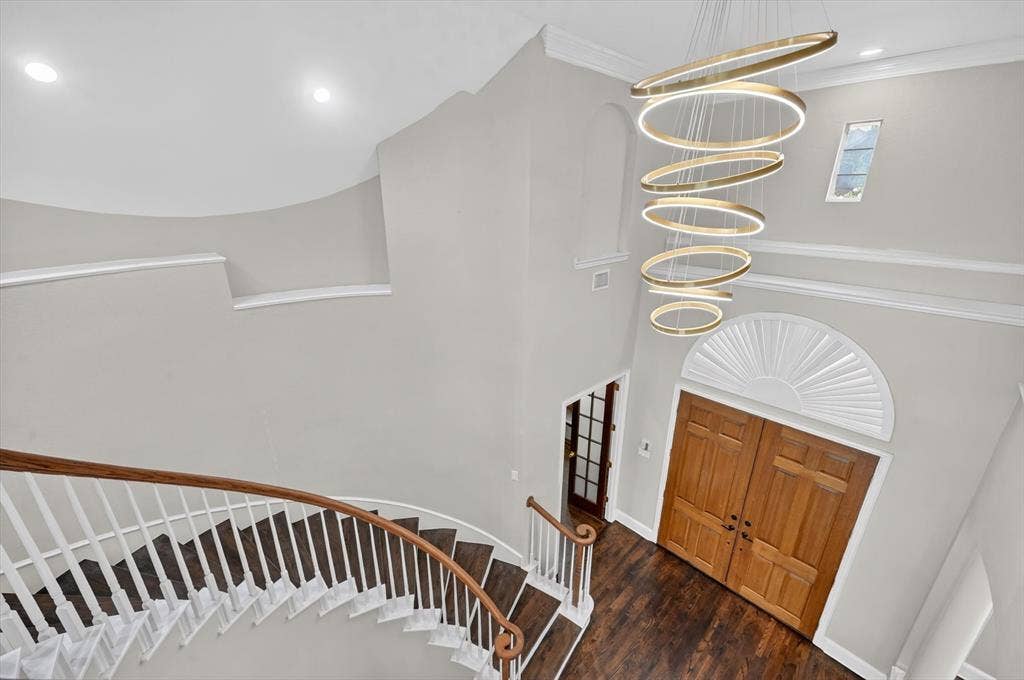 4437 Lone Tree Drive, Plano, TX 75093 Grand entryway featuring a curved staircase with wood-finish treads and white risers, a multi-tiered circular chandelier, double wood-paneled entry doors, and an arched fanlight window