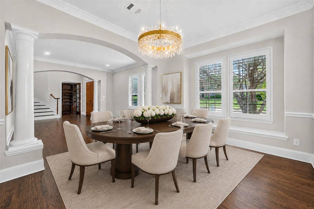 4437 Lone Tree Drive, Plano, TX 75093 Formal dining area featuring rich wood-finish flooring, a tiered crystal chandelier, and white plantation shutters