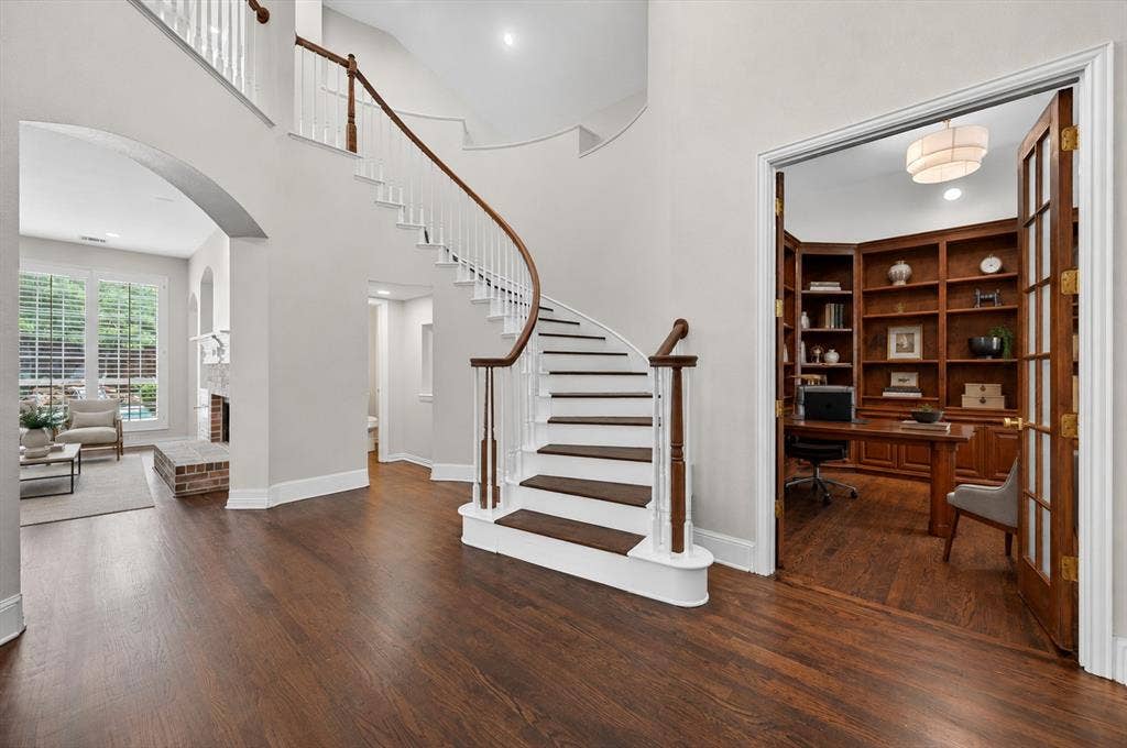 4437 Lone Tree Drive, Plano, TX 75093 Grand curved staircase with a wood-finish handrail and balusters