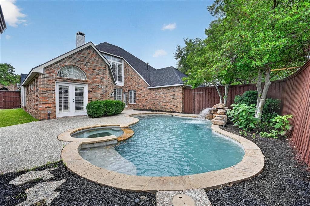 4437 Lone Tree Drive, Plano, TX 75093 Backyard oasis featuring a curvilinear pool with an integrated spa and rock waterfall