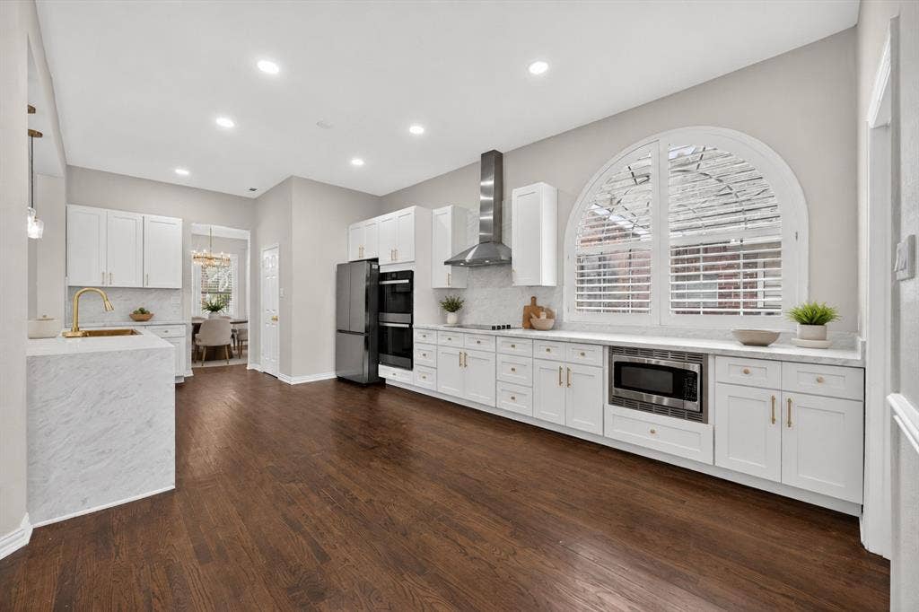 4437 Lone Tree Drive, Plano, TX 75093 Spacious kitchen featuring rich wood-finish flooring and an expansive arched window with plantation shutters