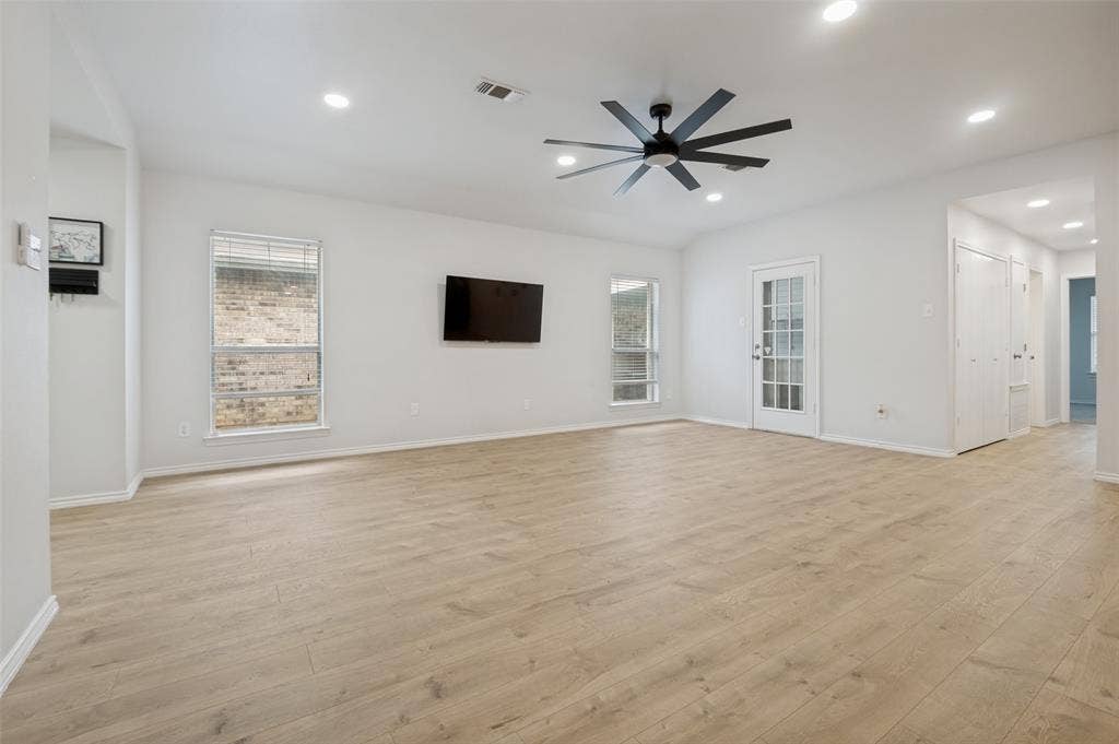 Spacious room featuring light wood-finish flooring, recessed lighting, and a modern ceiling fan