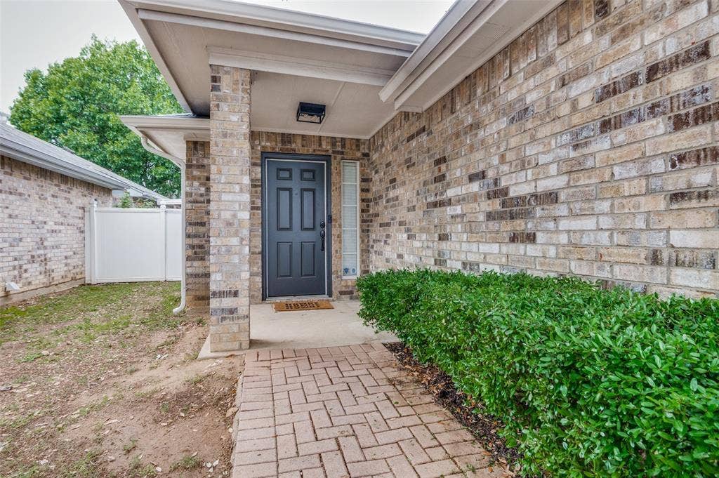 Brick exterior featuring a paneled entry door, a sidelight window, and a covered porch