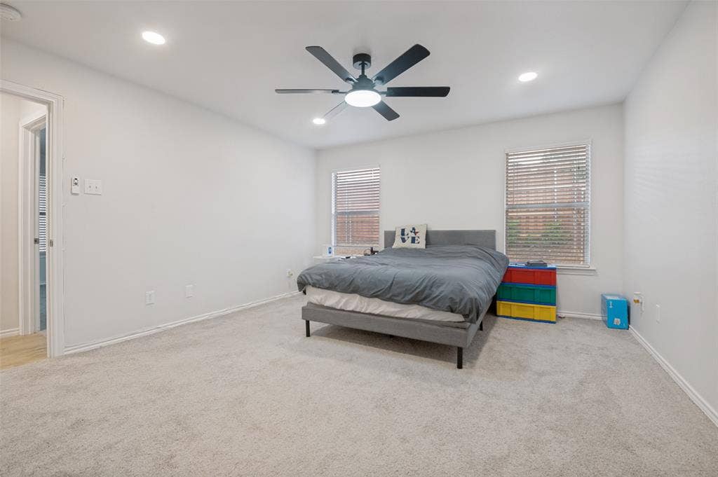 Spacious room featuring light-colored carpeting, recessed lighting, and a ceiling fan