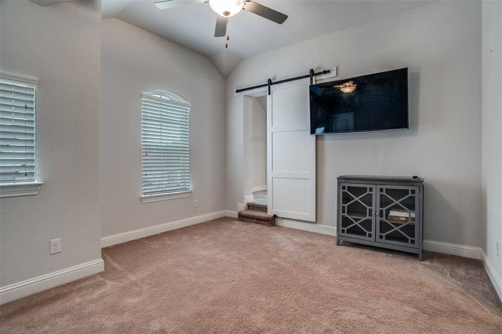2811 Killdeer Trail, Prosper, TX 75078 Unfurnished bedroom with a barn door, light colored carpet, a ceiling fan, and vaulted ceiling