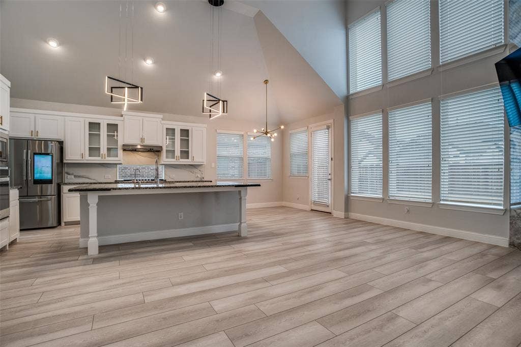 2811 Killdeer Trail, Prosper, TX 75078 Kitchen with glass insert cabinets, white cabinets, a high ceiling, stainless steel appliances, and decorative backsplash