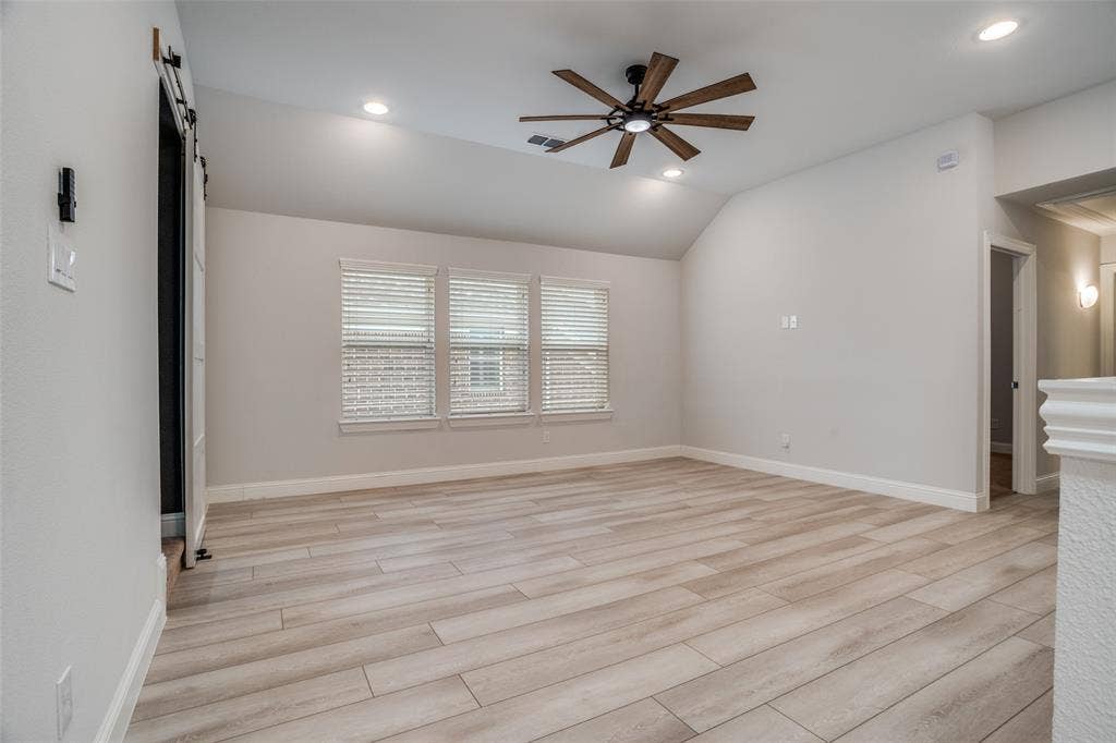 2811 Killdeer Trail, Prosper, TX 75078 Spare room with ceiling fan, a barn door, light wood-type flooring, recessed lighting, and lofted ceiling