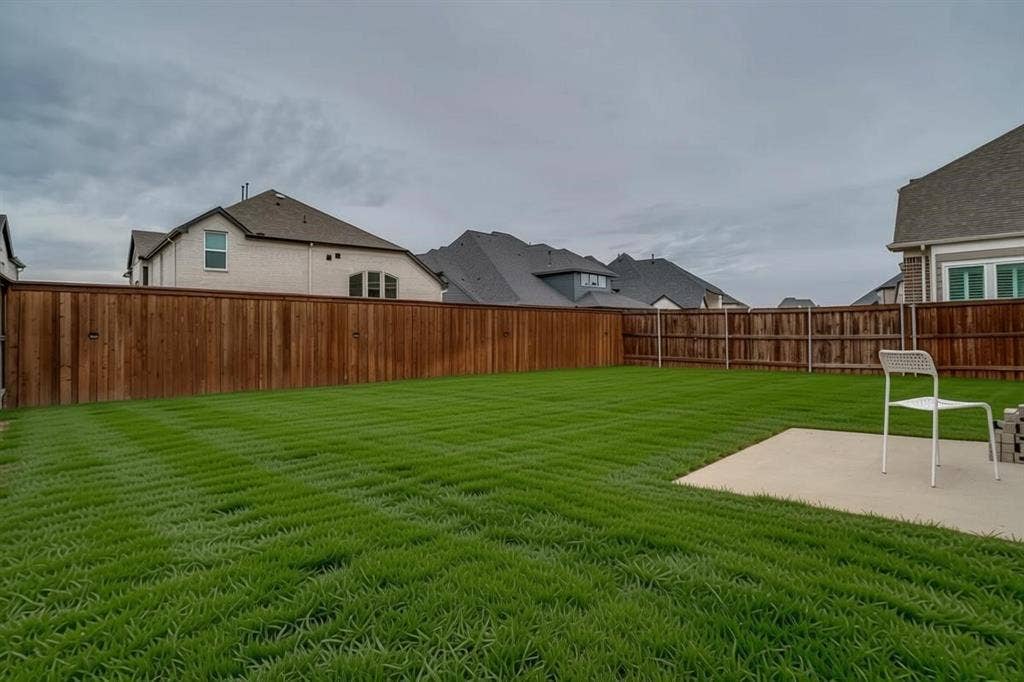 2811 Killdeer Trail, Prosper, TX 75078 Expansive backyard featuring a manicured lawn, a full wood privacy fence, and a concrete patio