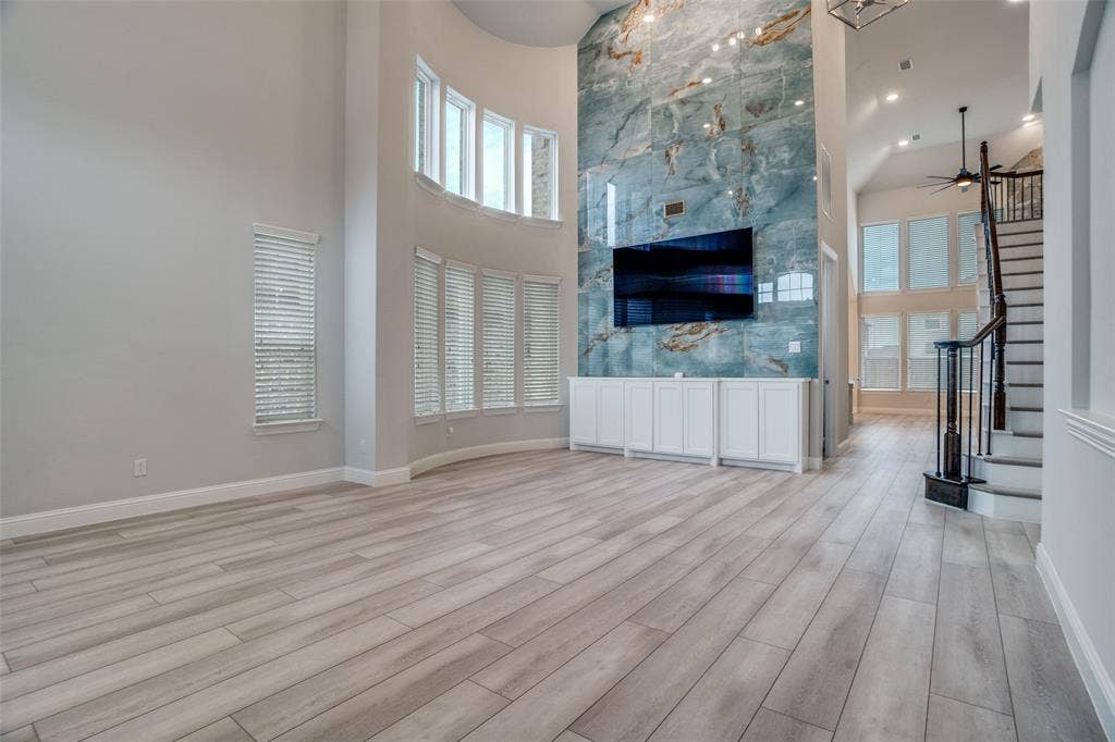 2811 Killdeer Trail, Prosper, TX 75078 Unfurnished living room featuring a high ceiling, light wood-type flooring, and a ceiling fan