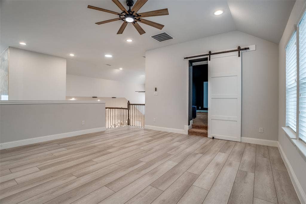 2811 Killdeer Trail, Prosper, TX 75078 Unfurnished room with a barn door, a ceiling fan, lofted ceiling, light wood finished floors, and recessed lighting