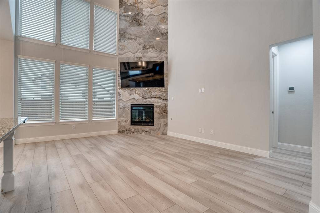 2811 Killdeer Trail, Prosper, TX 75078 Unfurnished living room featuring a high ceiling, a premium fireplace, and light wood finished floors