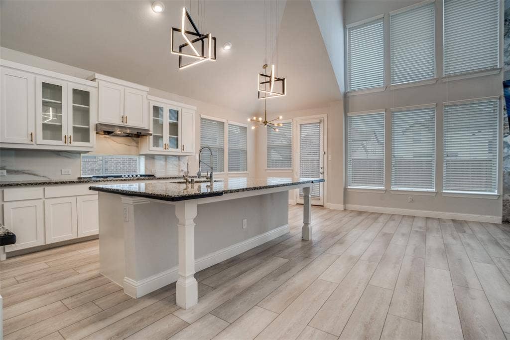 2811 Killdeer Trail, Prosper, TX 75078 Kitchen featuring a kitchen breakfast bar, white cabinets, dark stone counters, an island with sink, and light wood finished floors