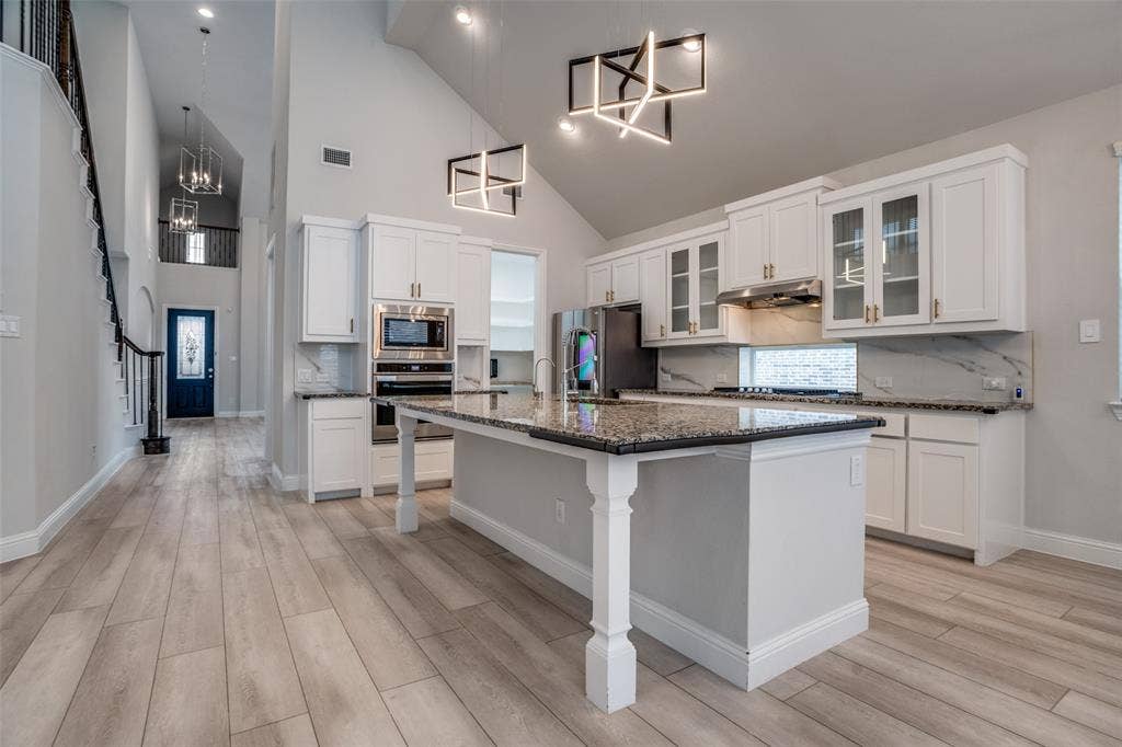 2811 Killdeer Trail, Prosper, TX 75078 Kitchen featuring backsplash, glass fronted cabinets, stainless steel appliances, white cabinets, and vaulted ceiling