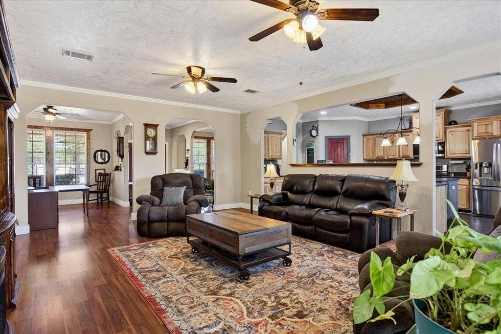 11591 Fm 59, Athens, TX 75751 Spacious living area featuring wood-finish flooring, light-toned walls, and multiple ceiling fans. Open concept floor plan.