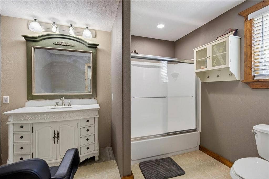 11591 Fm 59, Athens, TX 75751 4th Bathroom in Basement levelfeaturing a decorative vanity with an integrated sink, a large framed mirror, and a shower-tub combination with a sliding glass door. Next to this space is a Utility room.