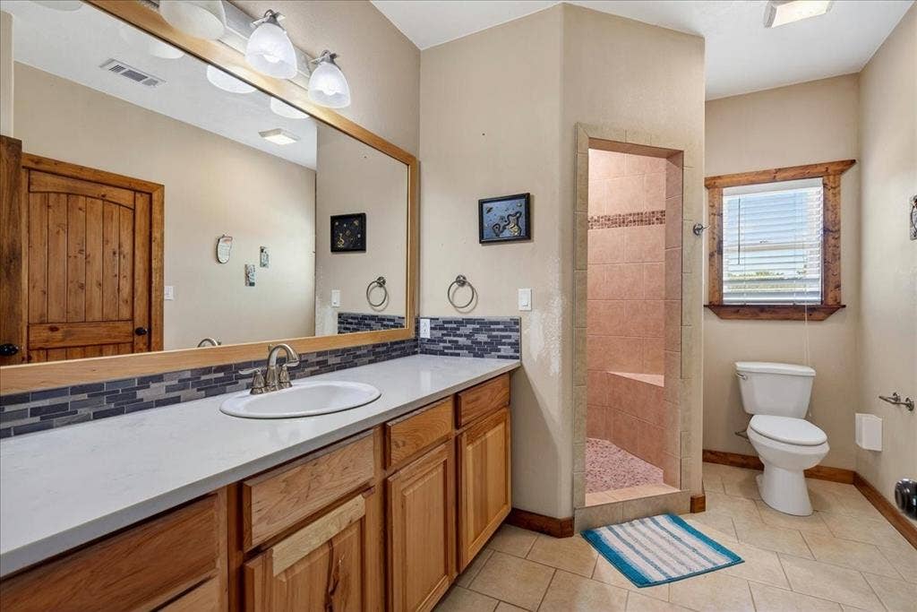 11591 Fm 59, Athens, TX 75751 2nd Primary Bathroom on level 1 featuring an oak vanity with light quartz countertop and undermount sink, backsplash, big mirror, cabinets and drawers. Large oversize walk-in shower with pebble stone, oversize walk-in closet, tile floor
