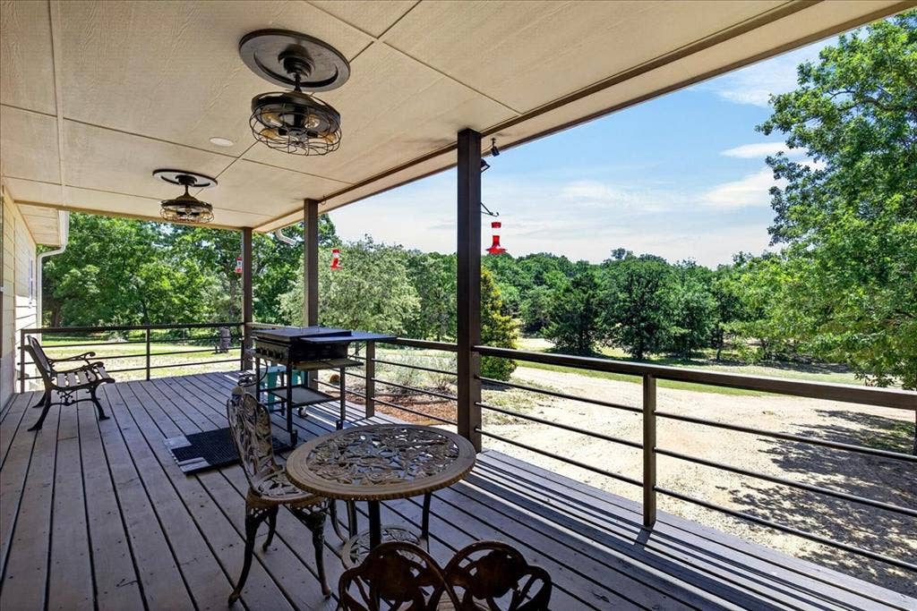 11591 Fm 59, Athens, TX 75751 Spacious covered back porch featuring wood-finish decking, dark metal railings, and two industrial-style ceiling fans. So much space for family and friends to enjoy the peaceful serenity of country living.