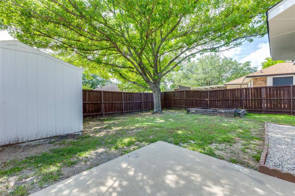 713 Bridgewater Lane, Mesquite, TX 75181 Expansive backyard featuring a mature shade tree, a white storage shed, and a privacy fence