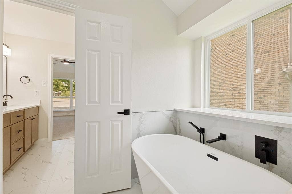 713 Bridgewater Lane, Mesquite, TX 75181 Freestanding soaking tub with matte black fixtures, set against a tiled accent wall and large windows