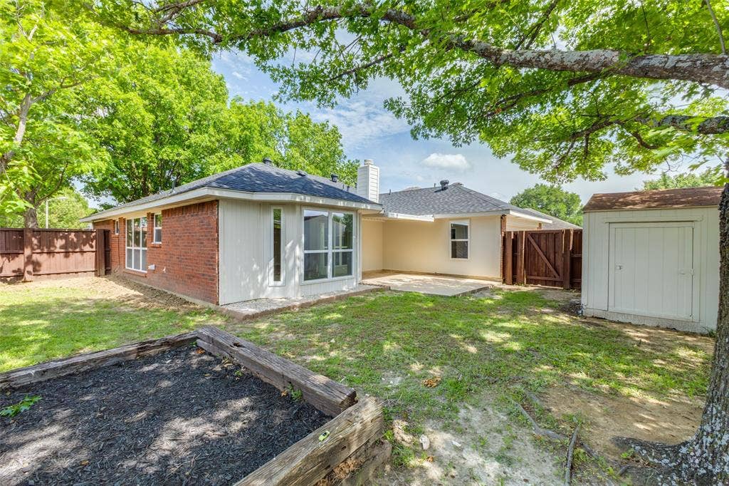 713 Bridgewater Lane, Mesquite, TX 75181 Expansive backyard featuring a brick and siding exterior, a concrete patio, a privacy fence, a storage shed, and a raised garden bed