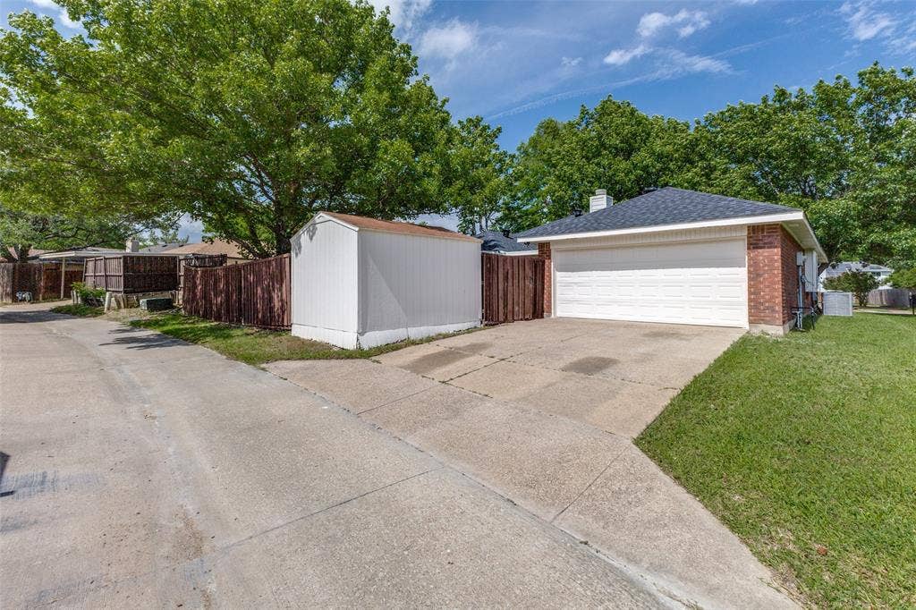 713 Bridgewater Lane, Mesquite, TX 75181 Brick exterior with a white garage door, dark shingle roof, and concrete driveway