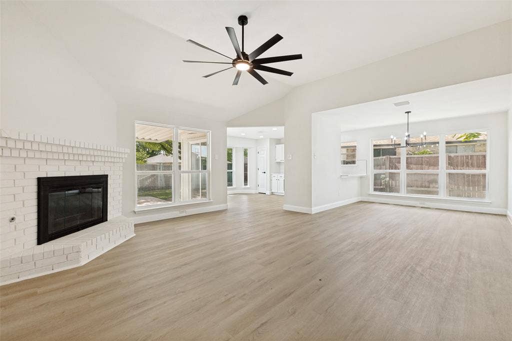 713 Bridgewater Lane, Mesquite, TX 75181 Open concept living area featuring wood-finish flooring, a white brick fireplace, vaulted ceilings, and a modern ceiling fan