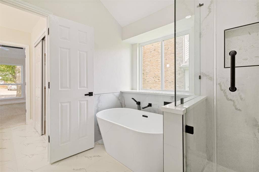 713 Bridgewater Lane, Mesquite, TX 75181 Bathroom featuring a freestanding tub with a wall-mounted faucet, a glass-enclosed shower, and white tile flooring
