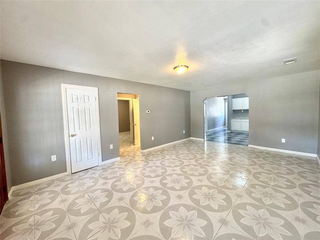 Spacious room featuring patterned tile flooring, light gray walls, and white baseboards