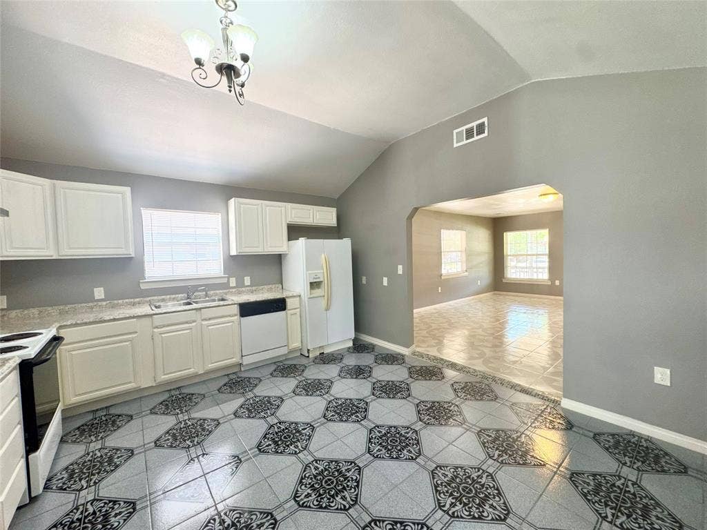 Kitchen featuring patterned tile flooring, white cabinetry, a double basin sink, and a black dishwasher