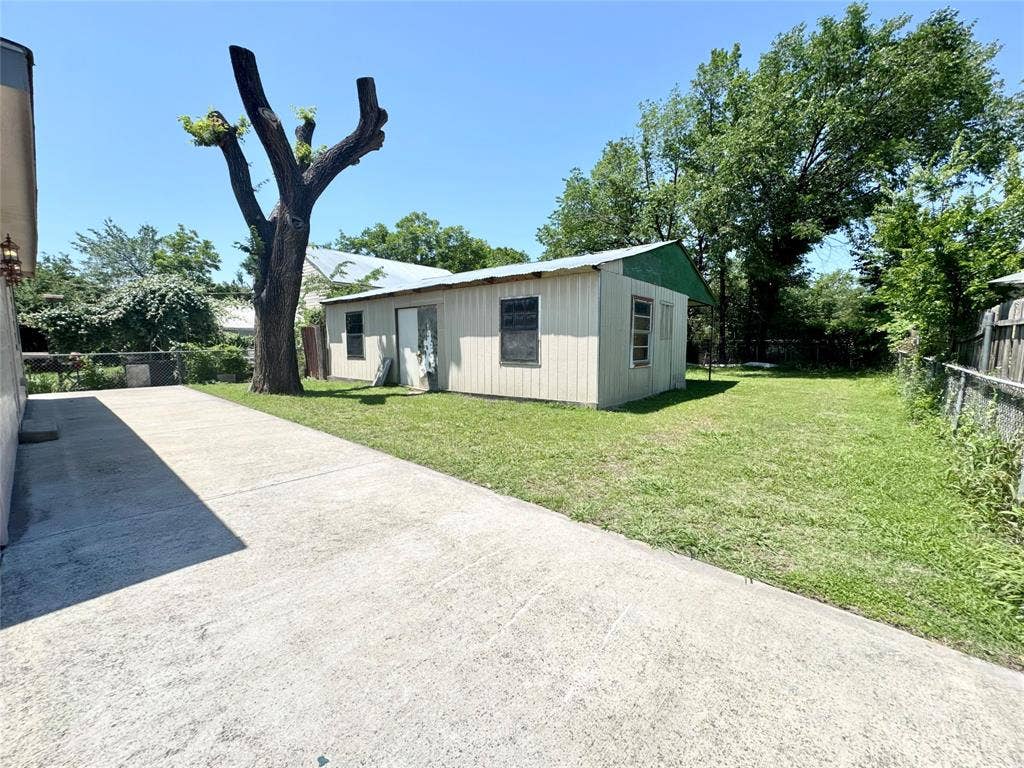Concrete driveway leading to a detached structure with a metal roof