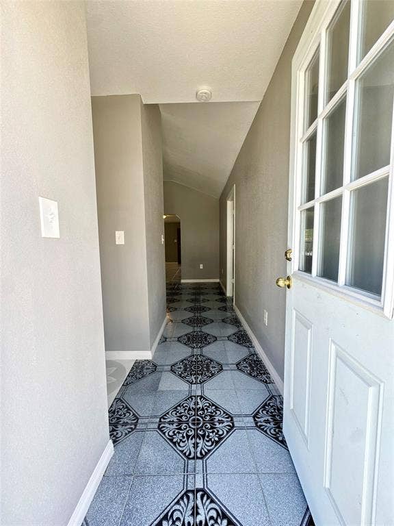 Entryway featuring patterned tile flooring, a white paneled front door with glass inserts, and a brass door handle