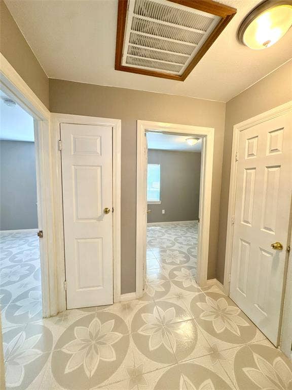 Hallway featuring patterned tile flooring, warm neutral wall tones, and multiple panel doors