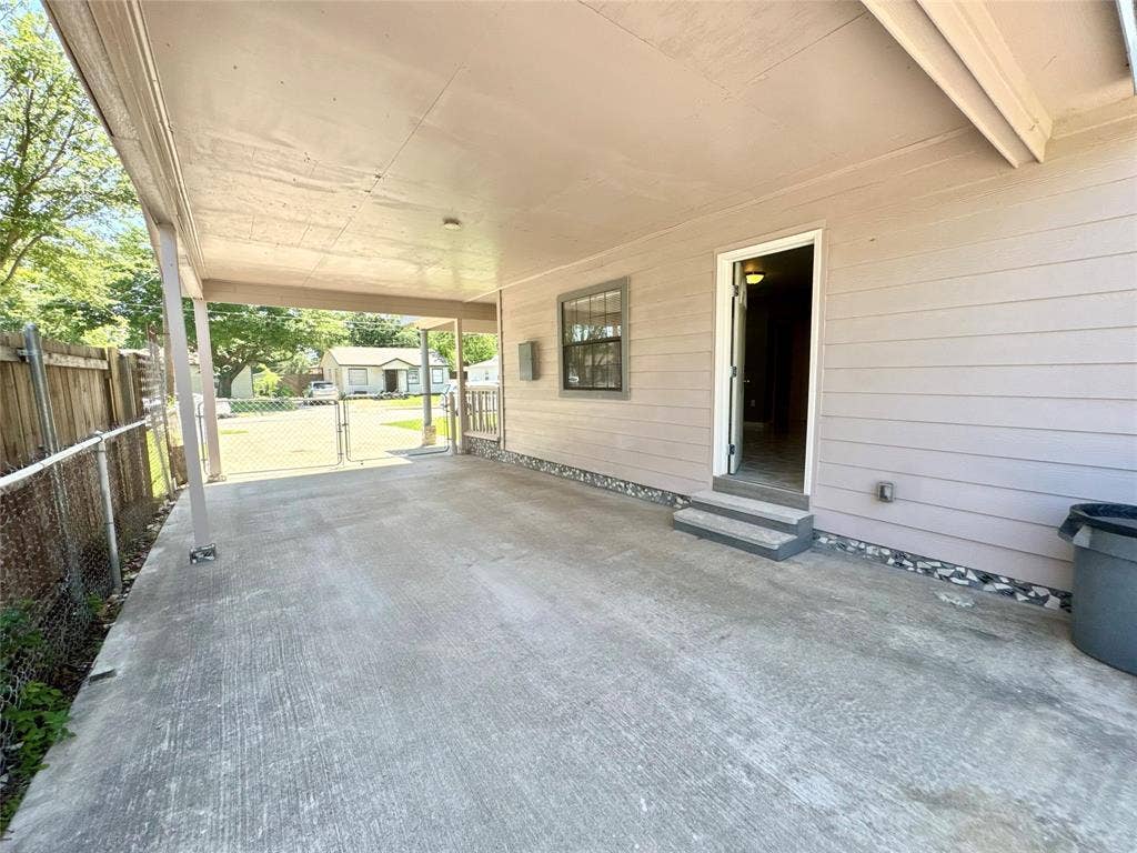Covered concrete patio with a paneled exterior wall, a single entry door, and two concrete steps