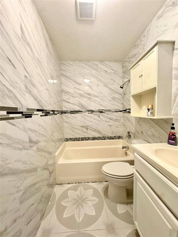 Bathroom featuring a bathtub with shower, toilet, and vanity with integrated sink