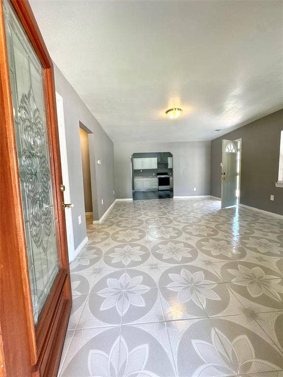 Spacious main living area featuring patterned tile flooring, light gray wall finishes, and a decorative glass-paneled entry door